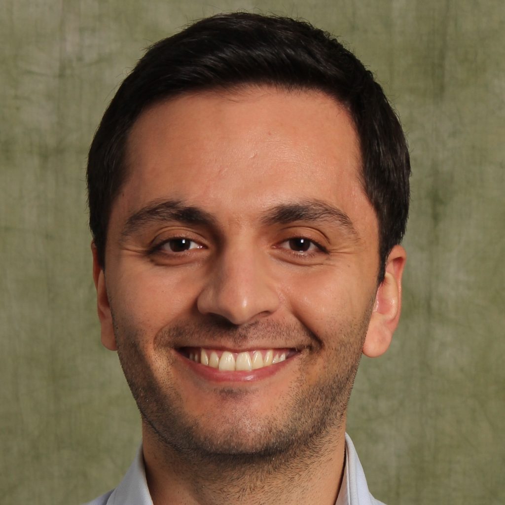 Dark brown haired man smiling.